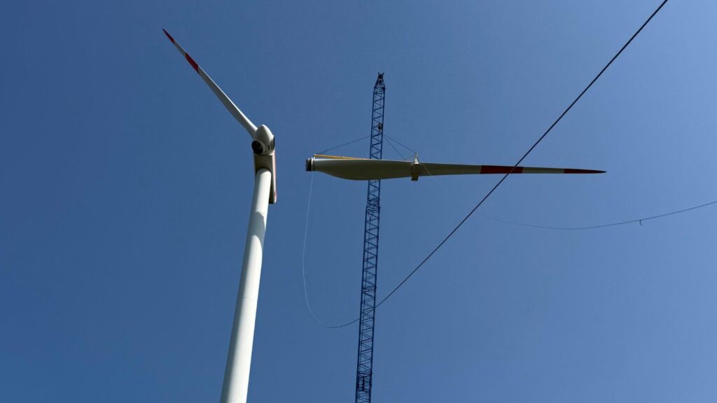 Kran neben einer Windenergieanlage bei Arbeiten am Rotor