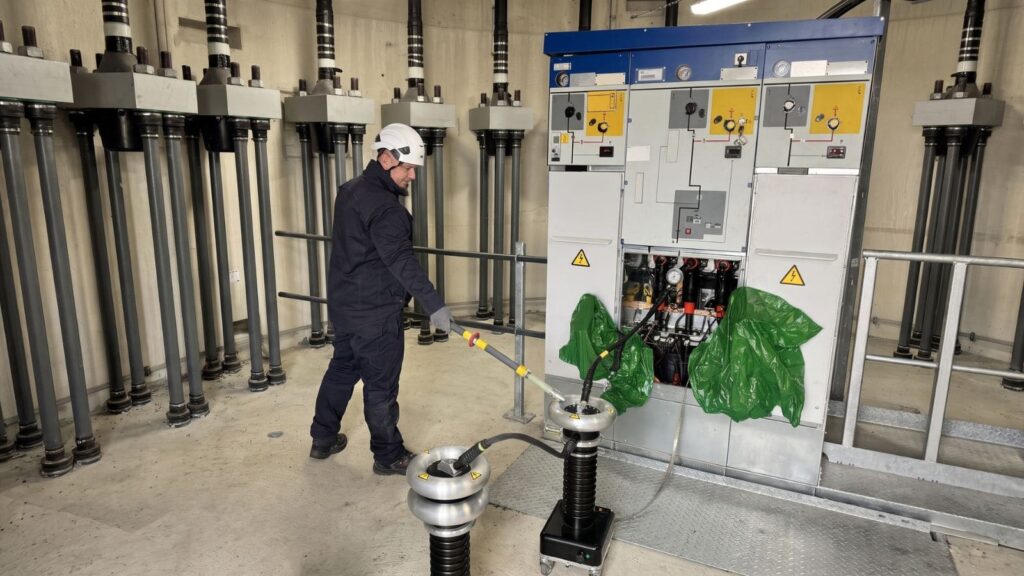 Techniker prüft eine Mittelspannungsschaltanlage mit angeschlossenem Prüfgerät